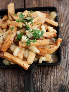 french fries with garlic and parsley in a black tray on a wooden table top