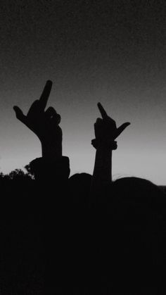 the silhouettes of two people with their hands in the air