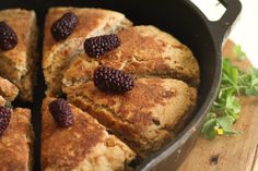 a pan filled with bread and raspberries on top of a wooden table