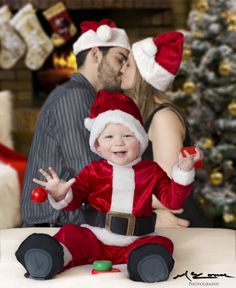 a baby dressed as santa clause sitting on a table