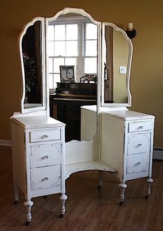 a white vanity with two drawers and a mirror on top of it in front of a window