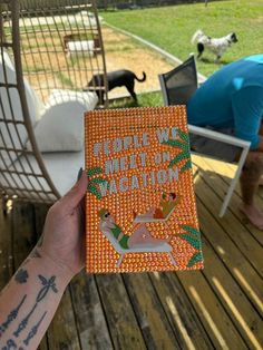 a person holding up an orange book with animals on it