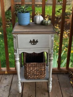 a small table with a basket on top of it and two pumpkins sitting next to it