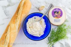 a blue bowl filled with whipped cream next to a loaf of bread