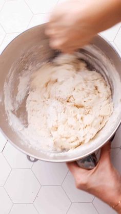 a person mixing dough in a metal bowl