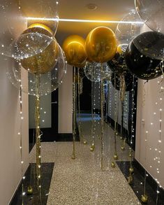 balloons and streamers are hanging from the ceiling in front of a hallway decorated with lights