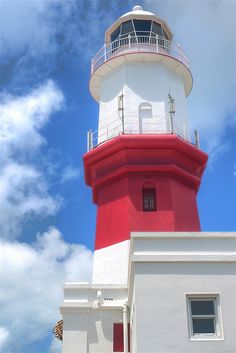 a red and white light house sitting on the side of a building under a cloudy blue sky