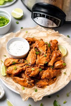 a plate with chicken wings and garnishes next to an instant pot