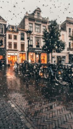 rain is falling down on the street in front of buildings