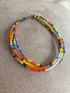 multicolored beaded bracelet with metal clasp on white fabric background, closeup