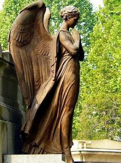 a statue of an angel is shown in front of a building with trees behind it