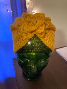 a yellow knitted hat sitting on top of a green vase