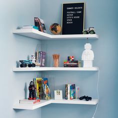 two white shelves with books and toys on them in a room that has blue walls