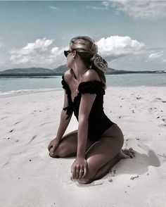 a woman sitting on top of a sandy beach