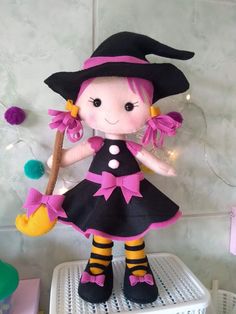 a stuffed doll dressed in black and pink holding a broom on top of a shelf