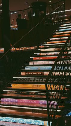 many books are stacked on top of each other in the same row, with stairs leading up to them