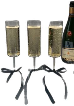 three champagne flutes are lined up in front of a bottle