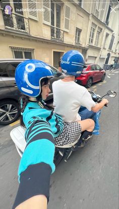 two people riding on the back of a scooter