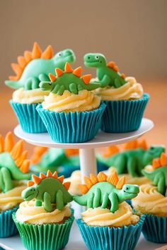 cupcakes decorated with green and orange frosting are arranged on a cake stand