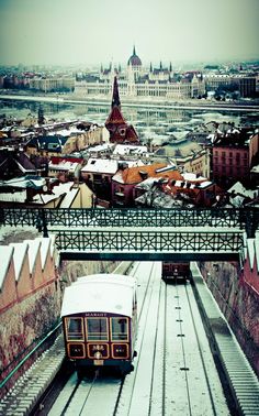 two trains traveling down tracks next to each other in the middle of snow covered city