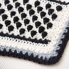 a black and white crocheted afghan on top of a bed next to a pillow