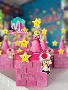 a nintendo mario birthday cake topper on a table with pink and yellow stars in the background