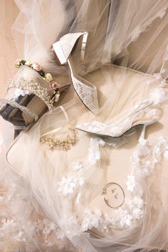 wedding shoes and tiara laying on top of a veiled cloth covered tablecloth