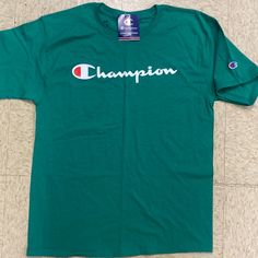 This Champion Shirt Is A Wonderful Green In Color And A Medium In Size . This Is An Irregular Stamped At Company . All The Regular Stuff Is Therr . Relaxed Fit Green Shirt With Text Print, Green Letter Print Shirt For Streetwear, Green Logo Print Shirt For Summer, Green Graphic Tee Shirt With Text Print, Green Crew Neck Top With Text Print, Green Graphic Tee With Text Print, Green Short Sleeve Shirt With Logo Print, Green Logo Print Summer Shirt, Green Long Sleeve Tops With Logo Print