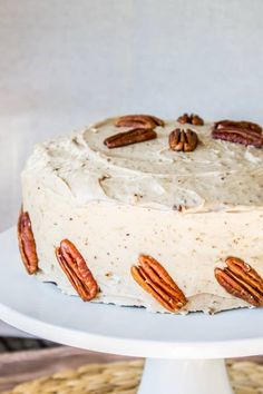 a cake with frosting and pecans sitting on top of a white platter