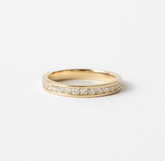 a yellow gold wedding band with small diamonds on it, set against a white background