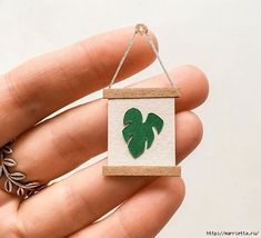 a hand holding a small ornament with a green leaf design on it's side