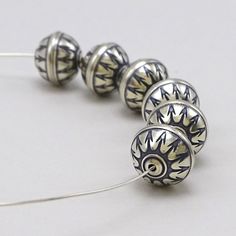 five silver colored beads with designs on them sitting next to each other in the middle of a white surface