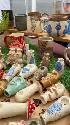 a table topped with lots of ceramic cups and vases on top of green grass