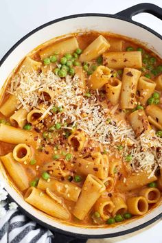 pasta with peas and parmesan cheese in a skillet on top of a striped towel