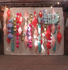 an art exhibit with colorful paper hanging from the ceiling and lights on the wall behind it