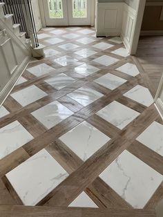 a white and brown tile floor in a house with stairs leading up to the front door