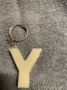 a keychain with the letter y on it is laying on a gray surface