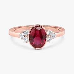 an oval shaped ruby and diamond ring with three diamonds on the band, set in 18k rose gold