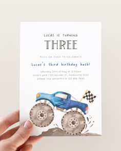 a hand holding up a birthday card with a blue monster truck on it's front