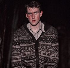 a man standing in the dark wearing a sweater