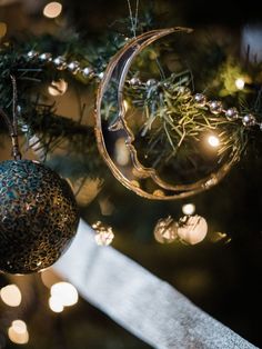 an ornament hanging from a christmas tree with lights in the background and on top of it