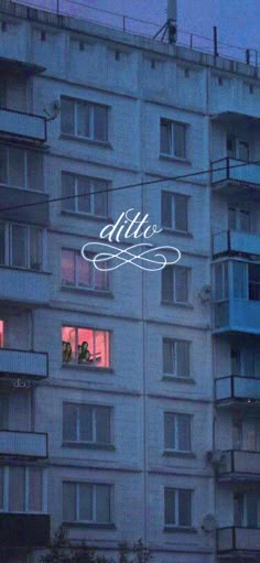 an apartment building with people looking out the windows at night and one person standing in the window