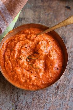 a wooden spoon in a bowl filled with red sauce