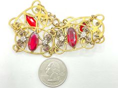 "This lovely bracelet features oval bezel set rhinestones in a deep ruby red color. The stones are flanked by white enamel flowers with red leaves that coordinate with the stones. These stones and enamel are all set in antique brass links. This wide, delicate bracelet has all the hallmarks of a Neiger piece (although these were not signed, so it's a bit hard to be sure). In any event, this is a prime example of Art Deco Czech jewelry. CONDITION/SIZE: Excellent vintage condition. About 7.5\" long Vintage Ruby Jewelry For Parties, Vintage Red Bracelets For Wedding, Vintage Red Bracelet For Wedding, Collectible Red Filigree Jewelry, Vintage Red Wedding Bracelet, Red Oval Art Deco Jewelry, Vintage Red Jewelry With Stone Setting, Red Vintage Jewelry With Stone Setting, Vintage Red Jewelry With Stones