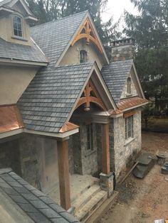 a house that is being built with stone and metal shingles on the front porch