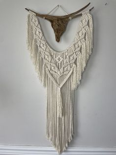 a white wall hanging with an animal's head on it and some fringes