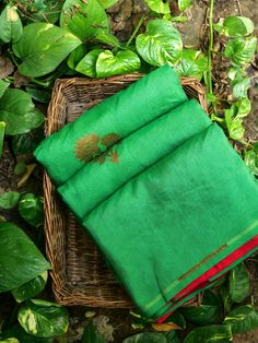 a green cloth sitting on top of a wicker basket next to some greenery