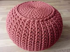 a pink knitted poufce sitting on top of a wooden floor