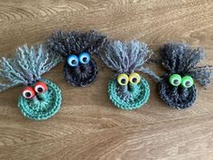 three crocheted monster heads sitting on top of a wooden floor