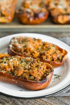 two stuffed peppers on a plate with other baked goods in the backgroung